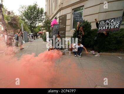 People hold signs and chant as they are shrouded by red smoke set off by demonstrators, near the White House, during a protest against racial inequality in the aftermath of the death in Minneapolis police custody of George Floyd, in Washington, U.S. June 6, 2020. REUTERS/Jim Bourg
