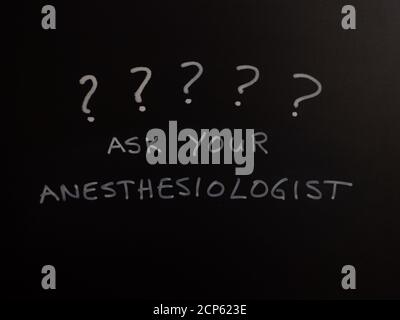 Ask your anesthesiologist written on chalkboard with question marks above. Stock Photo