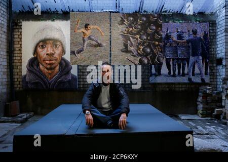 Street artist James Cochran, also known as Jimmy C, poses next to his spray painted pictures at the Pure Evil Gallery in London October 10, 2013. The paintings were originally inspired by the London riots in 2011. REUTERS/Stefan Wermuth (BRITAIN - Tags: ENTERTAINMENT SOCIETY)