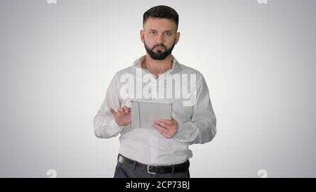 Serious young male executive using digital tablet and looking to Stock Photo
