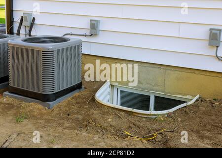 Air conditioning system assembled on performing preventive maintenance in a window well for basement construction new residential home Stock Photo