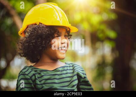 Happy little boy engineer wearing yellow safety helmet hard hat and laughing with happiness. Education and learning concept. Stock Photo