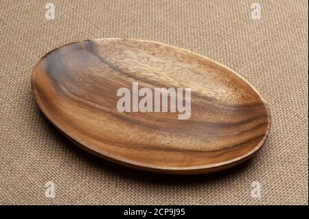 Empty wooden platter isolated on jute background. Close-up. Top view. Stock Photo