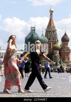 President and Chief Executive of the Armani Group Giorgio Armani (L) and a  Russian model look through a Russian newspaper as they walk towards Red  Square in Moscow, June 18, 2002. [Armani