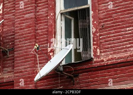 Satellite dish on wall of an old brick house