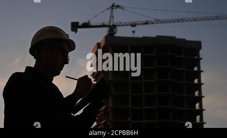 Engineer in a helmet writing check list. Stock Photo
