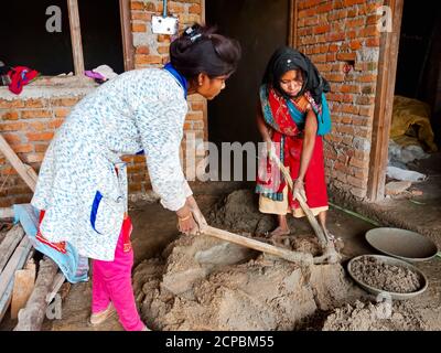 DISTRICT KATNI, INDIA - DECEMBER 18, 2019: Two indian village female labours making mixing building material from spade at home construction site. Stock Photo