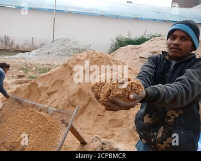 DISTRICT KATNI, INDIA - DECEMBER 18, 2019: An indian village male labour offering sand to camera for photograph at home construction site. Stock Photo