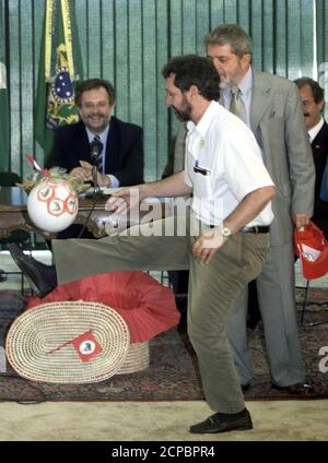 Landless Movement (MST) member Enio Bohnenberger juggles a soccer ball in front of Brazilian President Luiz Inacio Lula da Silva (R) as Agrarian Development Minister Miguel Rosseto (seated) looks on, in Brasilia, July 2, 2003. Lula da Silva held an emergency meeting with the nation's landless movement as armed conflict between peasants and landowners threatened to break out on his doorstep. The standoff 40 km (25 miles) from the presidential palace is just part of a wave of looting, blockades and protests by Brazil's Landless Workers Movement, or MST, to force Lula to make good on promises to 