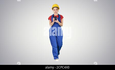 Female worker walking and using phone on gradient background. Stock Photo