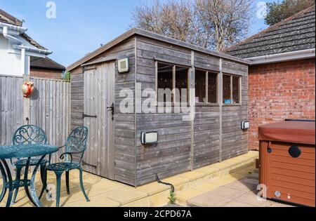 Private wooden windowed garden shed in a rear garden in the UK. Stock Photo
