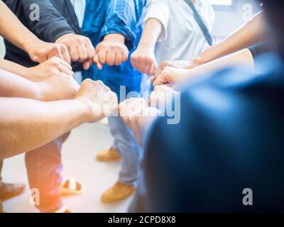 Close-up of hands many people putting circle their fists together as symbol of unity. Concept of teamwork and relationship Stock Photo