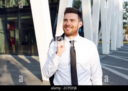 Businessman Walking on Sunny day with jacket on his Shoulder. Business man Smiling Stock Photo