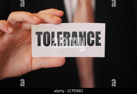 Tolerance words on a card in businessman hand. Social concept against discrimination at workplace Stock Photo