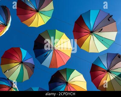 Two decorative colorful umbrellas hanging on ropes in the air on blue sky background. Horizontal picture Stock Photo