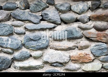 fragment of stone wall lined with cobblestones background texture Stock Photo