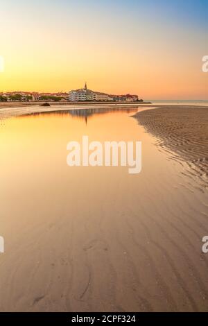 Colorful orange beach at sunset with ripple sand patterns from the receding tide and reflections on the water of the lagoon in a tranquil scenic lands Stock Photo