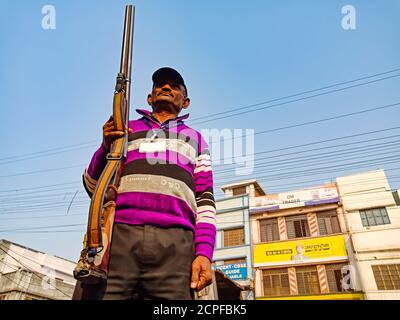DISTRICT KATNI, INDIA - JANUARY 18, 2020: An indian security guard holded rifle gun on blue sky background at road. Stock Photo