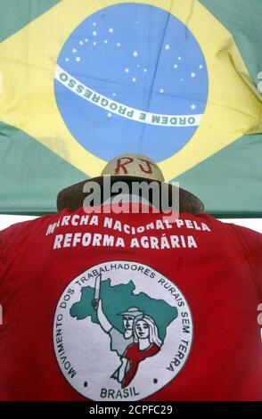 A member of Brazil's Landless Movement poses beneath the national flag atop Corcovado mountain in Rio de Janeiro, prior to launching a demand for large scale agrarian reform in the country, April 29, 2005. Brazil's rural workers will begin their 180 mile journey in the 'National March for Land Reform' on May 1 from the city of Goiania in central Brazil and converge on the capital of Brasilia 30 days later. REUTERS/Bruno Domingos  SM/GN