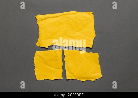 Torn real paper yellow color scraps on gray background. Top view Stock Photo