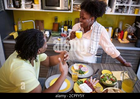 Happy Afro-American male and female eating in kitchen Stock Photo