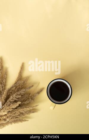 A cup of black tea in a ceramic cup with field herbs on a yellow background. Minimalism concept. Top view. Stock Photo