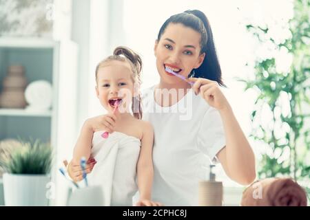 Happy family! Mother and daughter child girl are brushing teeth toothbrushes in the bathroom. Stock Photo