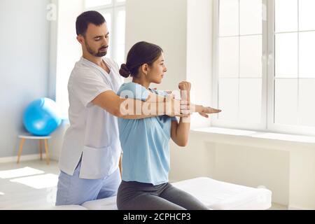 Physiotherapist and patient working on arm injury, doing medical exercise, stretching muscles Stock Photo