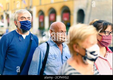 Crowd of adult people walking on city street with face mask on - New normal lifestyle concept - Focus on bald man with brown protective mask Stock Photo