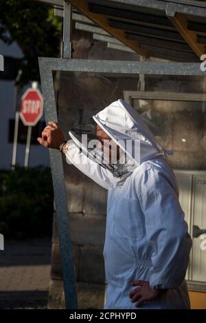 Beekeeper stands at a bus stop Stock Photo