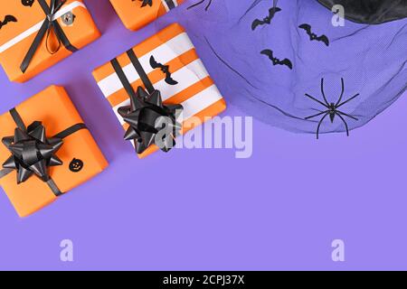 Gift boxes for Halloween with black ribbons and small bats and mesh with spiders on purple background with empty copy space Stock Photo
