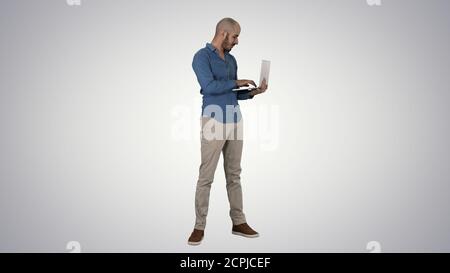 Young middle eastern businessman, standing and typing on laptop Stock Photo