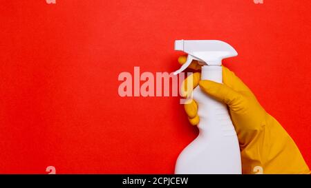 household cleaner, white spray in the hands with yellow rubber gloves on a red background. space for text. Stock Photo