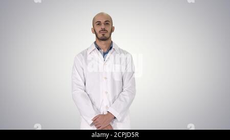 Standing young serious arab doctor on gradient background. Stock Photo