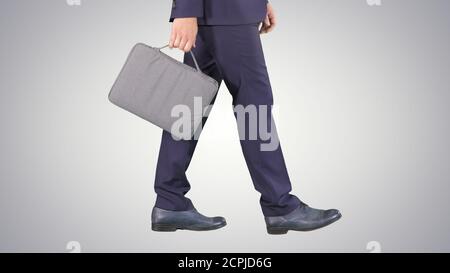 Handsome businessman in a suit walks with a briefcase on gradien Stock Photo
