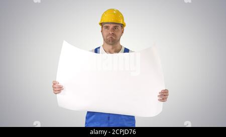 Construction worker checking blueprints on site on gradient back Stock Photo