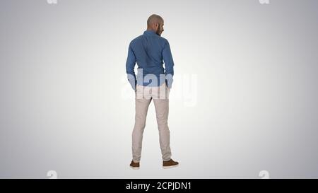 Arab in casual looking around with hands in pockets on gradient Stock Photo