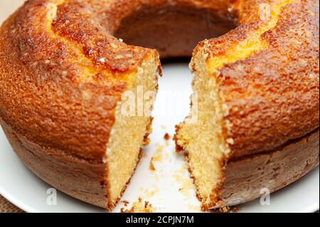 Cornmeal Cake (Bolo de Fubá) cut Brazilian style on a white plate. Isolated on jute. Front view. Close-up. Stock Photo