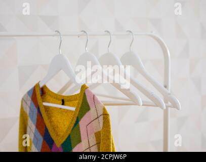 Knitted cardigan weighs on a white clothes hanger Stock Photo