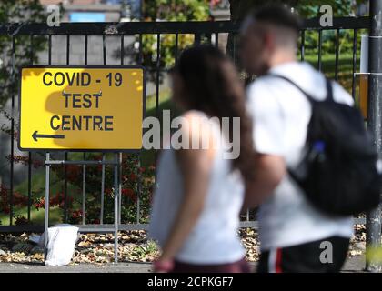People pass a COVID-19 test centre sign at the new walk-through testing centre at Glasgow Caledonian University's ARC sports centre, in central Glasgow which opened yesterday. Stock Photo