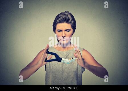 Conceptual creative shot of a man being clamped squeezed in female hands trying to resist pressure isolated on gray wall background Stock Photo