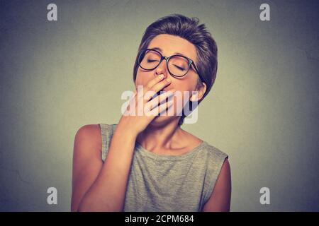 It is too early for meeting. Closeup portrait headshot sleepy young woman with hand over open mouth yawning eyes closed looking bored isolated gray ba Stock Photo