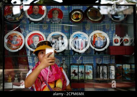 A woman takes a selfie in front of souvenirs featuring portraits of China's late Chairman Mao Zedong and China's President Xi Jinping outside a shop near the Forbidden City in Beijing, China, September 9, 2016. REUTERS/Thomas Peter