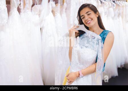 Young girl chooses a wedding dress. Satisfied girl with a dress in her hands Stock Photo