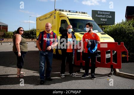 A group of Blackpool fans with two (right) wearing face masks next to an ambulance outside the ground before the Sky Bet League One match at Bloomfield Road, Blackpool. Stock Photo