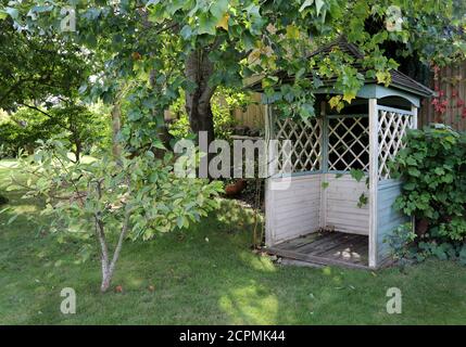 A classic gazebo nestled under a tree in the garden Stock Photo