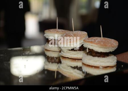 Three burgers in a row set on mirrored plate Stock Photo