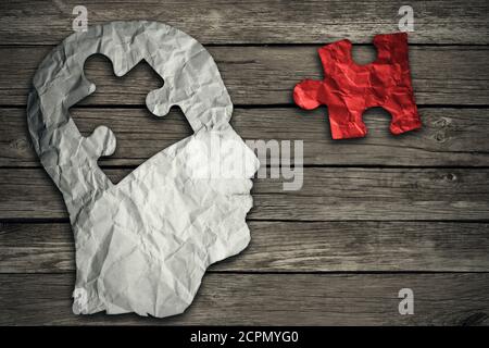 Puzzle head brain concept as a human face profile made from crumpled white paper with a jigsaw piece cut out on a rustic old wood background as a ment Stock Photo