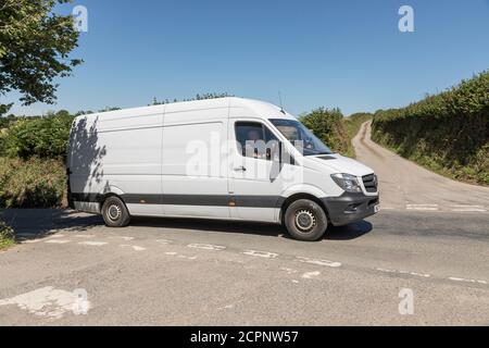 Mercedes delivery van driving along a country road in Cornwall. For white van man, tradesman's van, rural business. Stock Photo