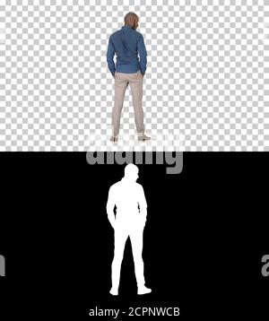 Arab in casual looking around with hands in pockets, Alpha Chann Stock Photo